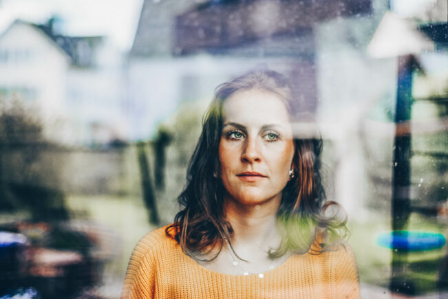 Young woman looks thoughtfully through the window